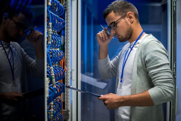 Data center technician reviewing a checklist while inspecting server rack cables